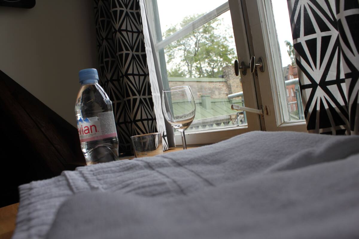 Une chambre d’hôtel avec un lit, une bouteille d’eau, un verre et une vue sur l’extérieur.