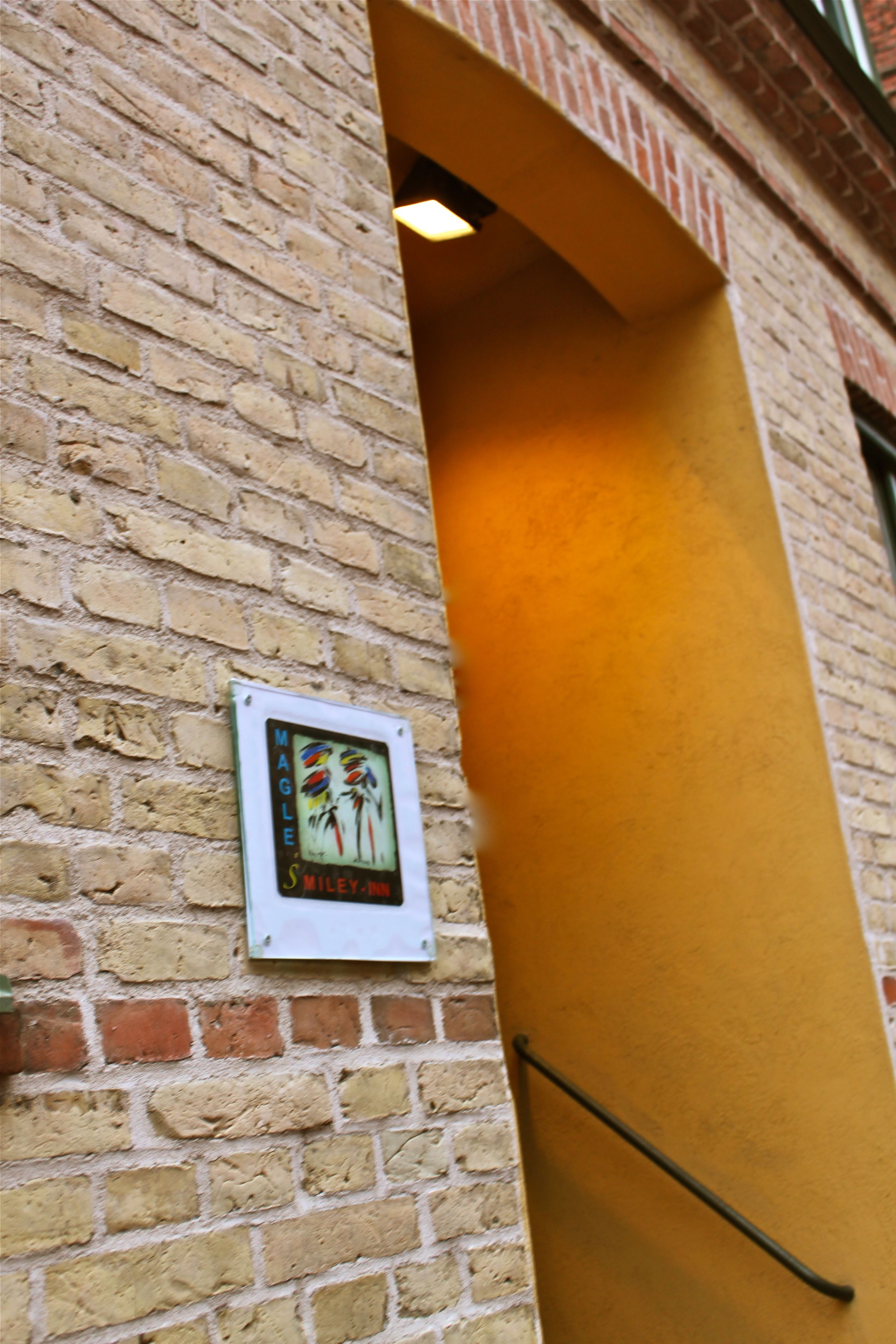 A brick wall with a small sign and a yellow door frame.