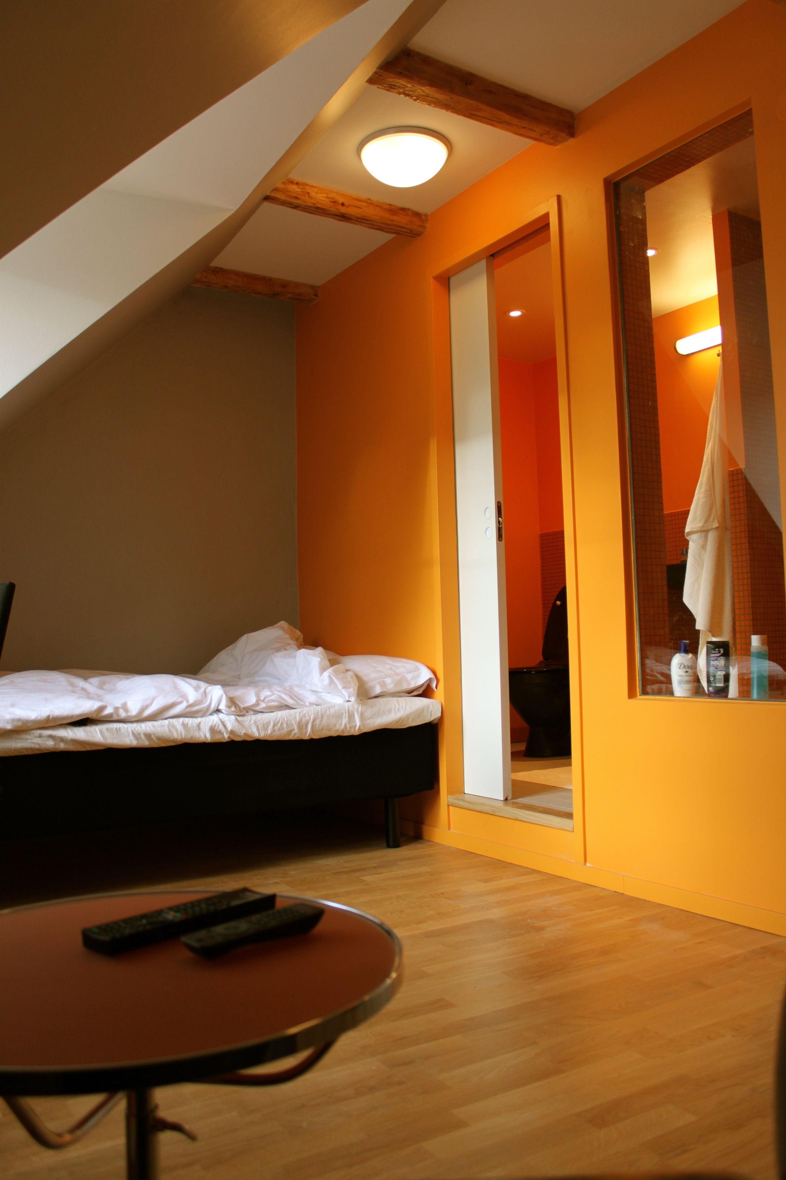 A bedroom with a bed, a round table, and a mirror.
