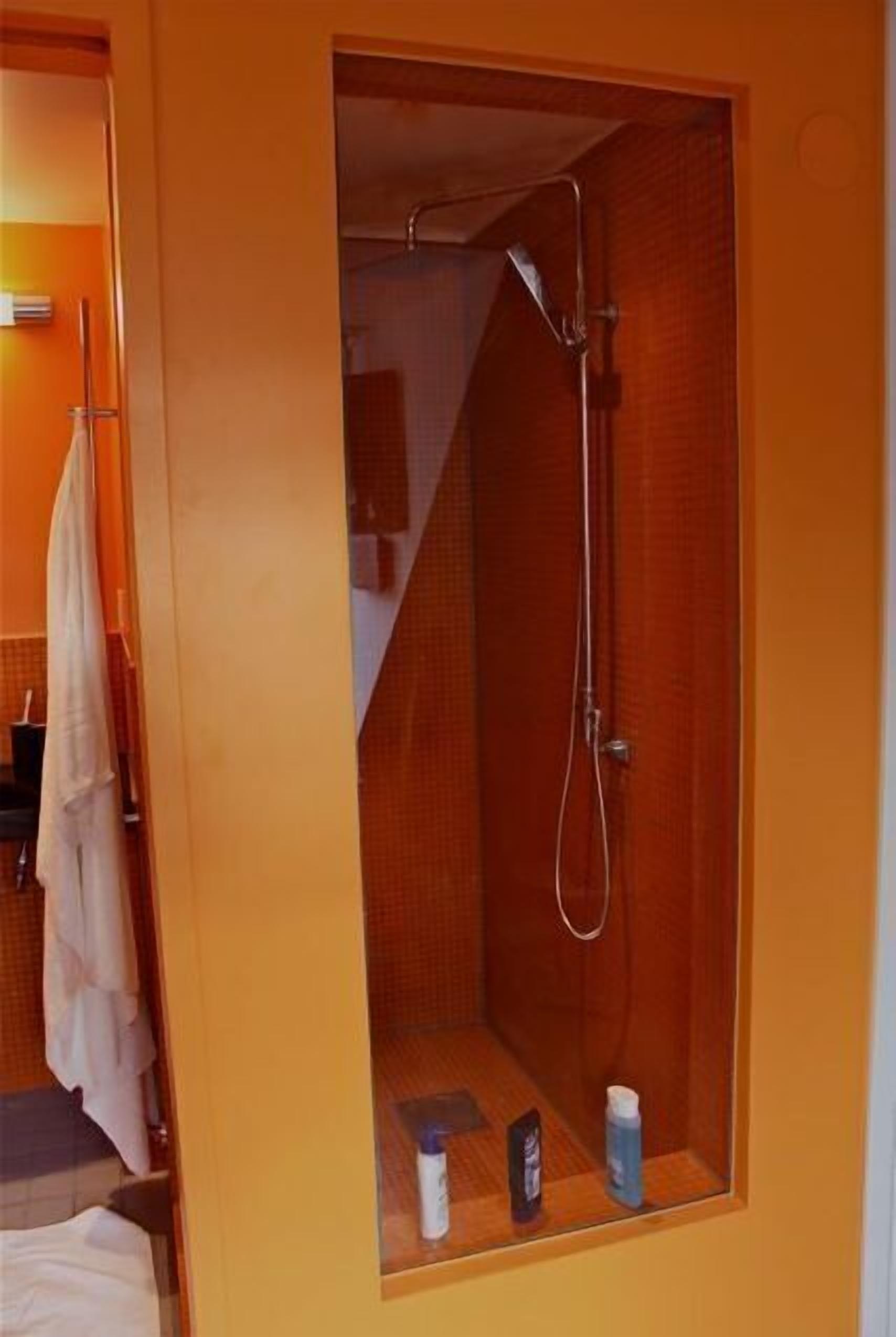 A small, enclosed shower area with a showerhead and a towel rack.