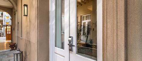 A white door with a glass panel, a small potted plant, and a lantern on the ground.