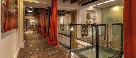 A modern interior with wooden flooring, glass railings, and red curtains.