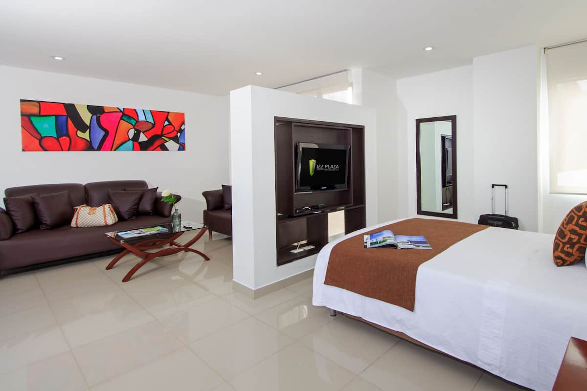 Een hotelkamer met een bed, een bank, een televisie, een spiegel en een raam.