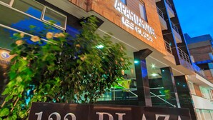 Une enseigne pour le 122 Plaza Apartahotel, avec une façade moderne en briques et des fenêtres illuminées.