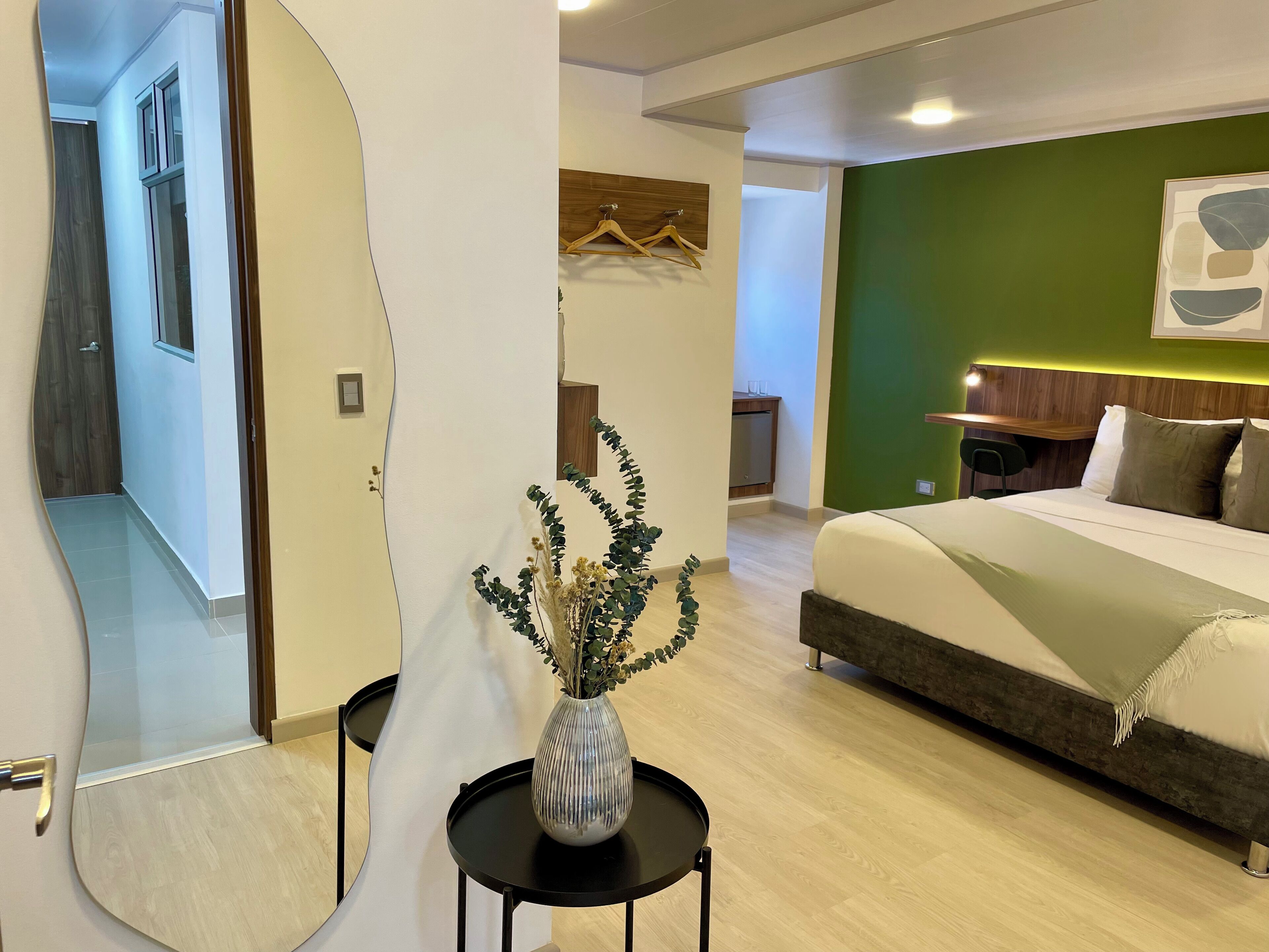 A modern bedroom with a bed, bedside table, and a vase with dried flowers.