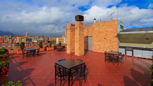 Une terrasse sur le toit, avec des murs en briques, des sièges extérieurs et une vue sur le paysage urbain.