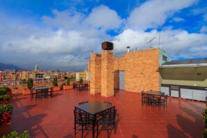 A rooftop patio with brick walls, outdoor seating, and a view of the cityscape.