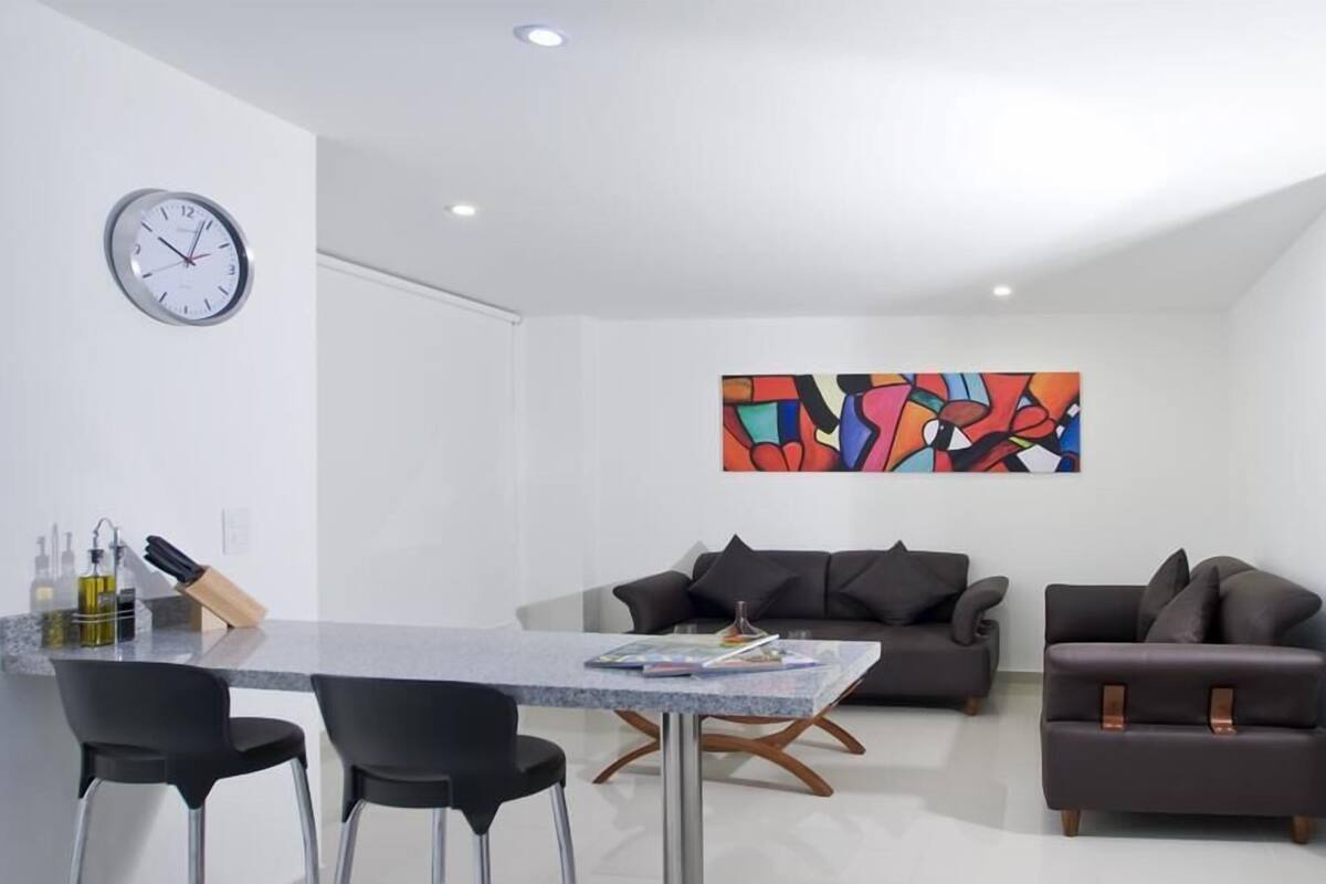 Een moderne woonkamer met een eethoek, een bank, een bijzettafeltje en een wandklok.