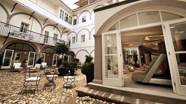Un patio con mobiliario exterior, una cinta de correr y un ventanal de vidrio que da a una habitación.