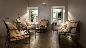 Una habitación acogedora con un sofá, dos sillones, una mesita y una ventana con vistas a la vegetación.
