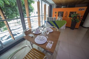 A dining area with a table set for two, a window view, and a plant on the side. - Hotel Golden Palermo (Medellín)