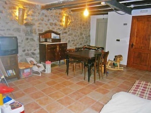 A dining area with a stone wall, wooden furniture, and a television.
