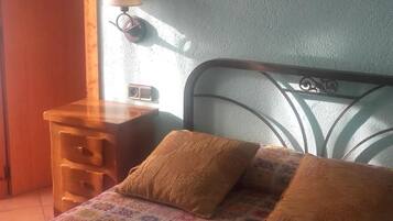 A bedroom with a bed, a nightstand, a lamp, and a wall art piece.