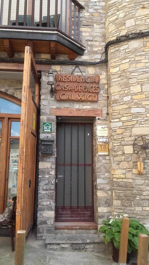 Un bâtiment en pierre avec une porte en bois et un balcon.