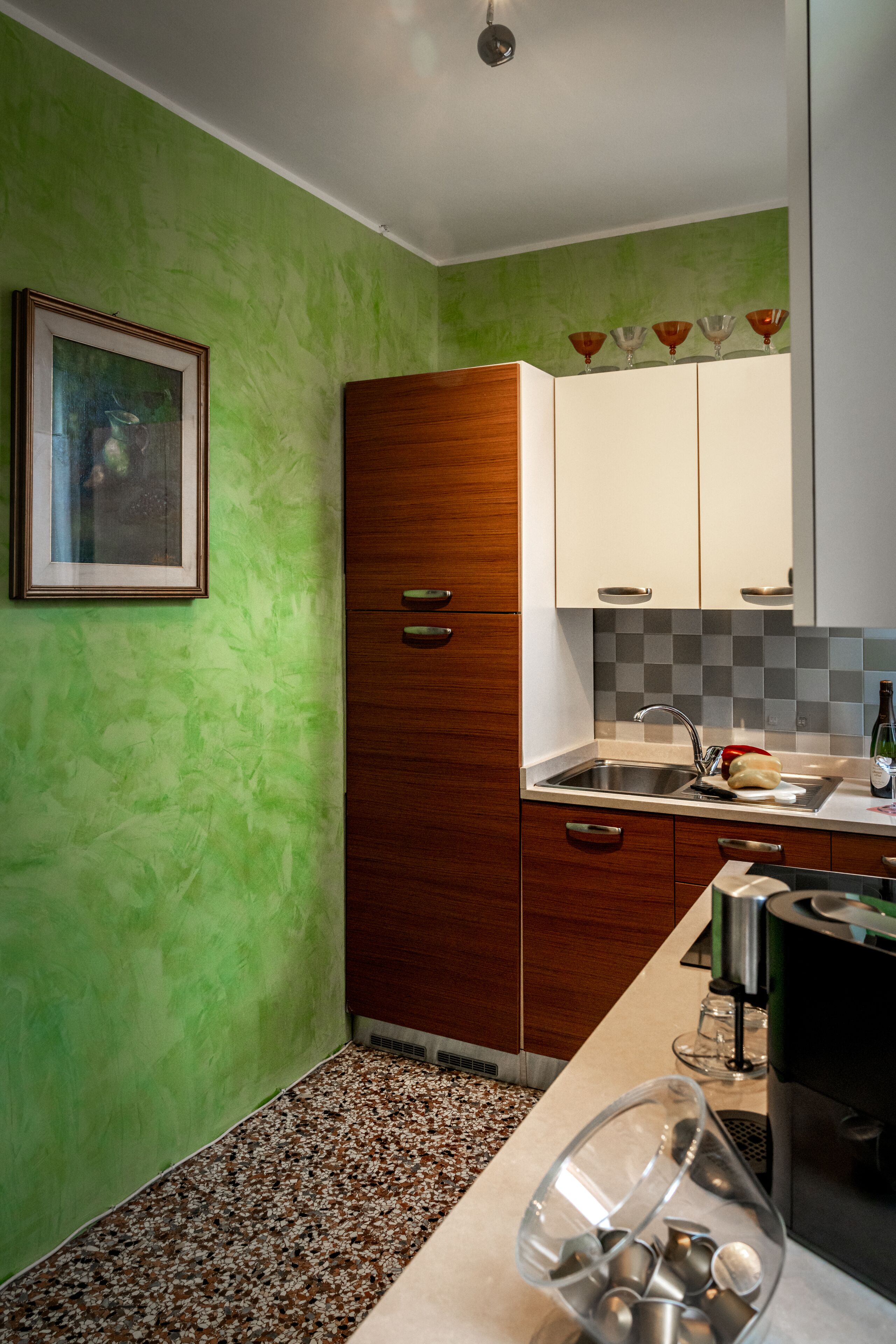 A kitchen with green walls, wooden cabinets, a sink, and a coffee machine.