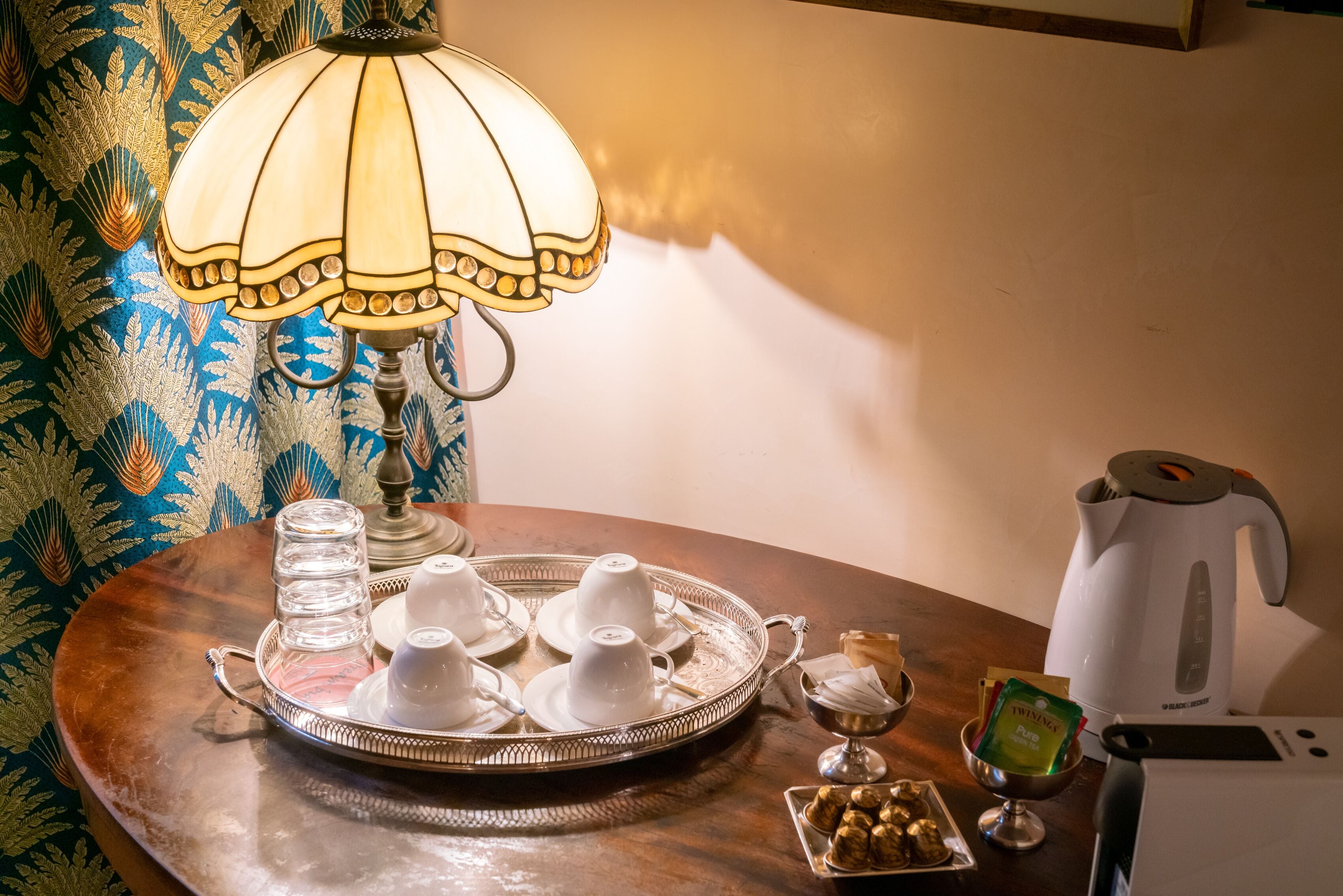 Una mesa con una bandeja de tazas blancas, una tetera y una hervidora.