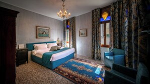 Un dormitorio con una cama grande, una silla, una araña de cristal y cortinas estampadas.
