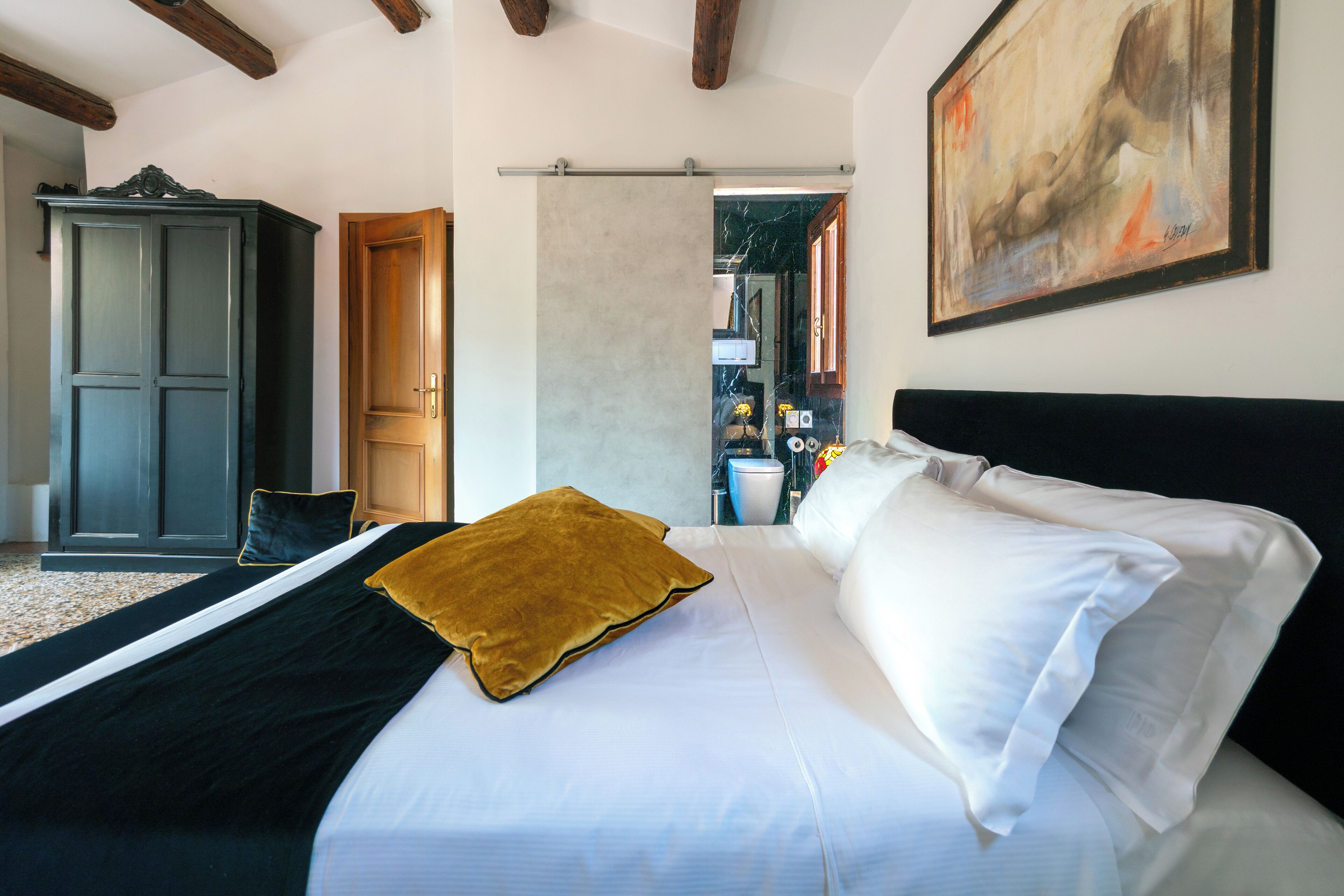 Un dormitorio con cama, armario y un cuadro en la pared.