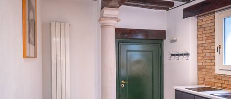 A kitchen with a long counter, a green door, and a brick wall.