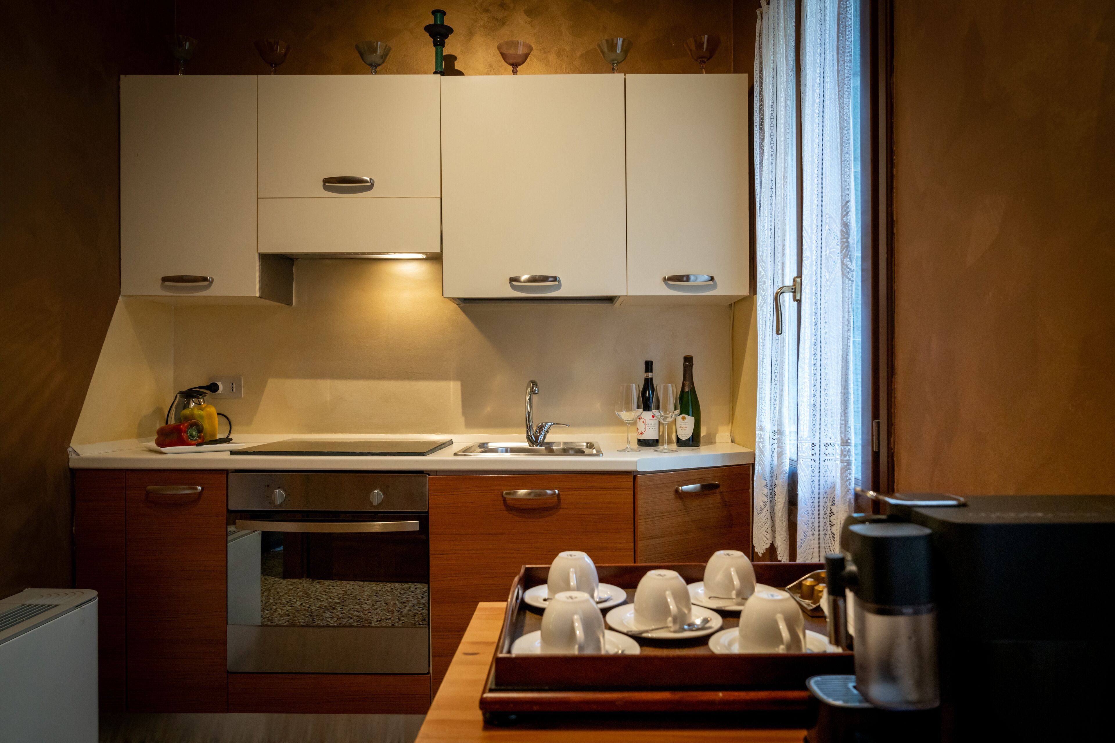 A compact kitchen with white cabinets, a sink, and a coffee machine.