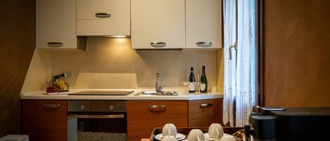A compact kitchen with white cabinets, a sink, and a coffee machine.