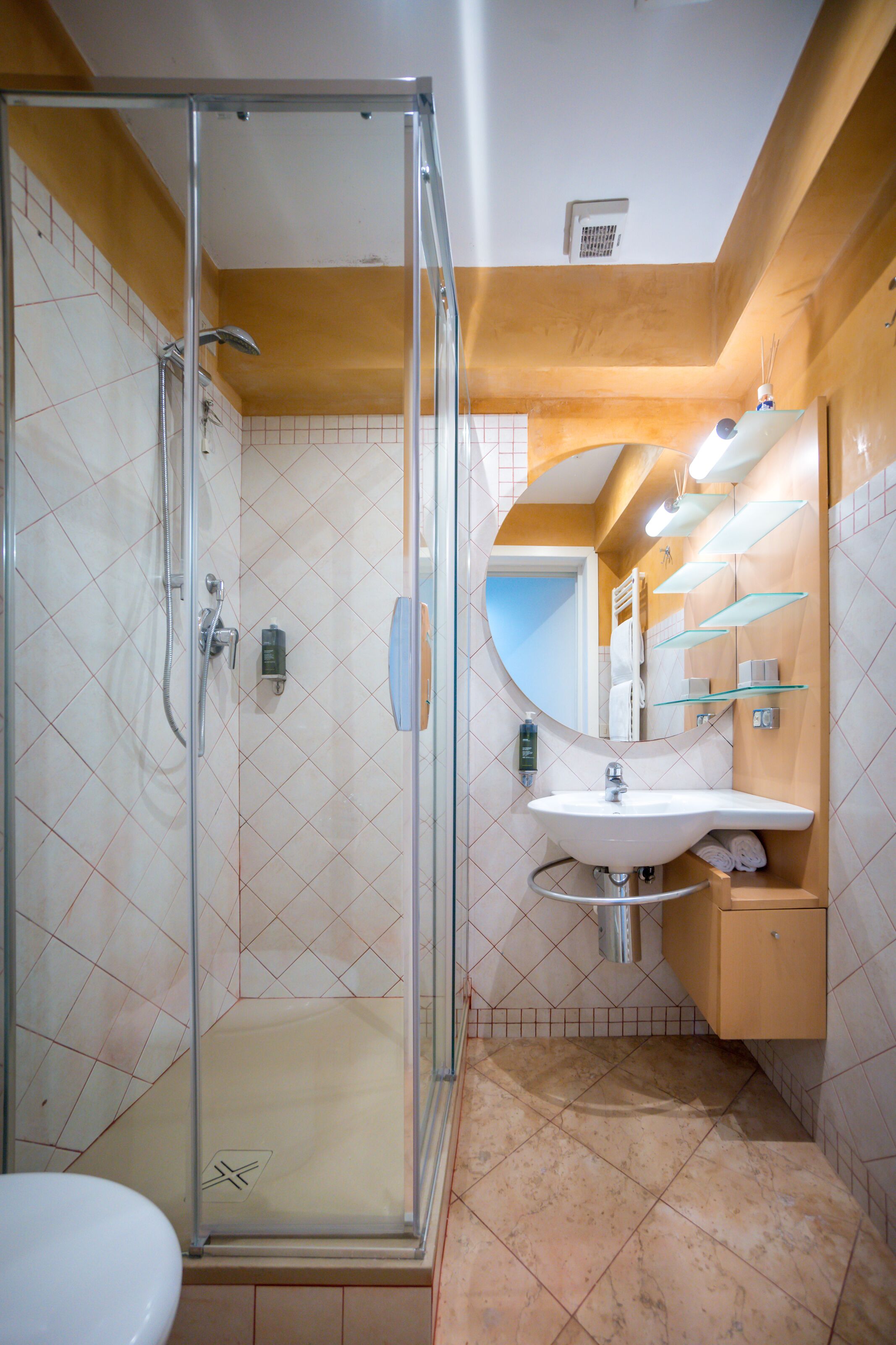 Un baño con cabina de ducha de vidrio, un lavabo con espejo y un inodoro.
