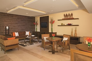 A modern living room with a sofa, chairs, a coffee table, and a TV mounted on the wall.