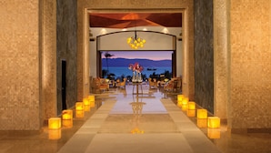 Un hall d’entrée avec vue sur la mer, un comptoir de réception et un espace détente avec des tables et des chaises.