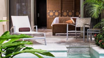 A pool area with a lounge chair, a sofa, and a dining table.