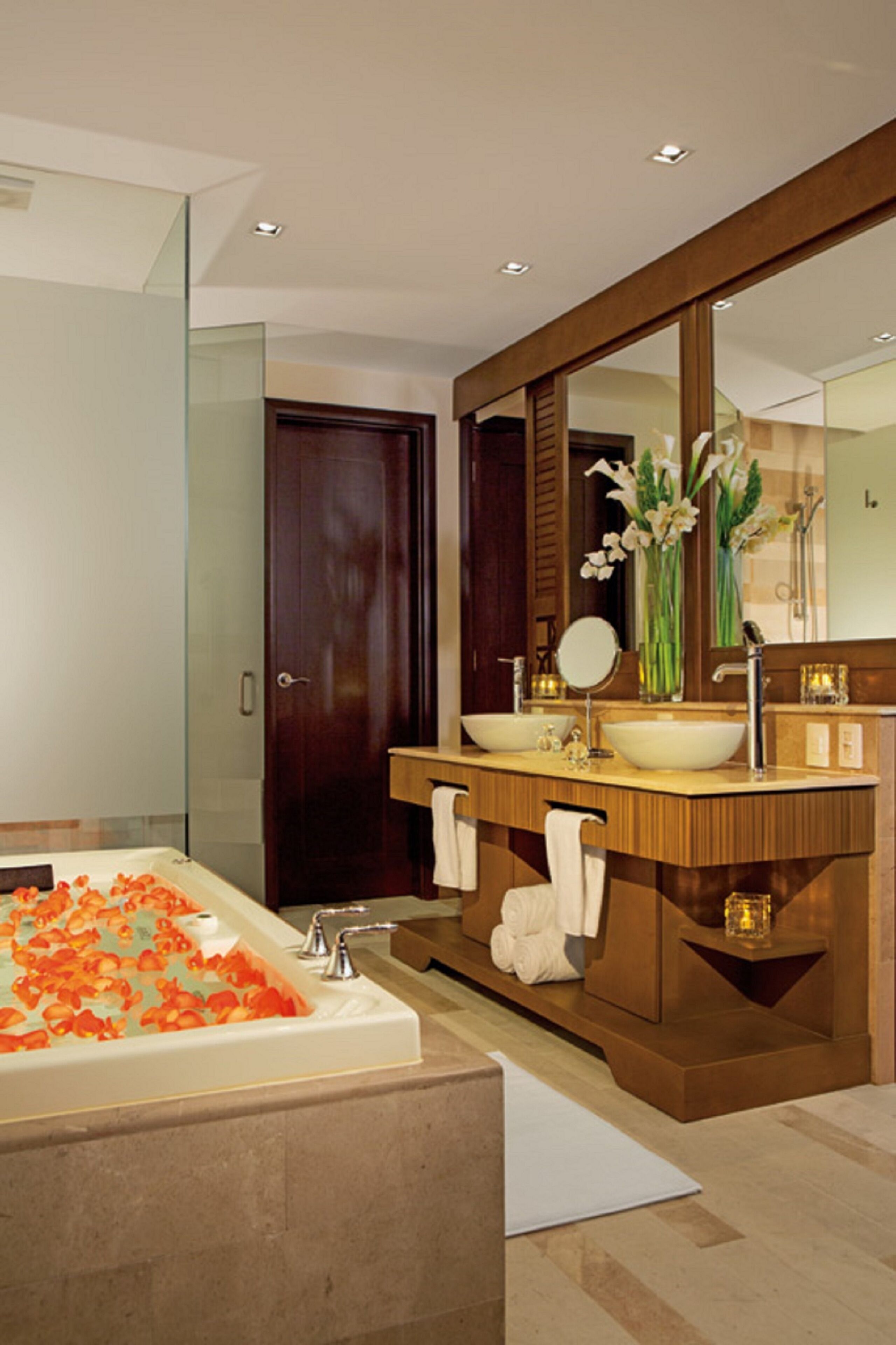 Un baño moderno con una bañera grande, dos lavamanos, un espejo y un mueble de tocador de madera.