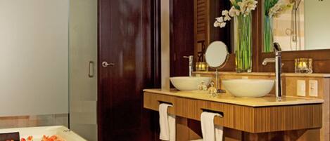 Un baño moderno con una bañera grande, dos lavamanos, un espejo y un mueble de tocador de madera.