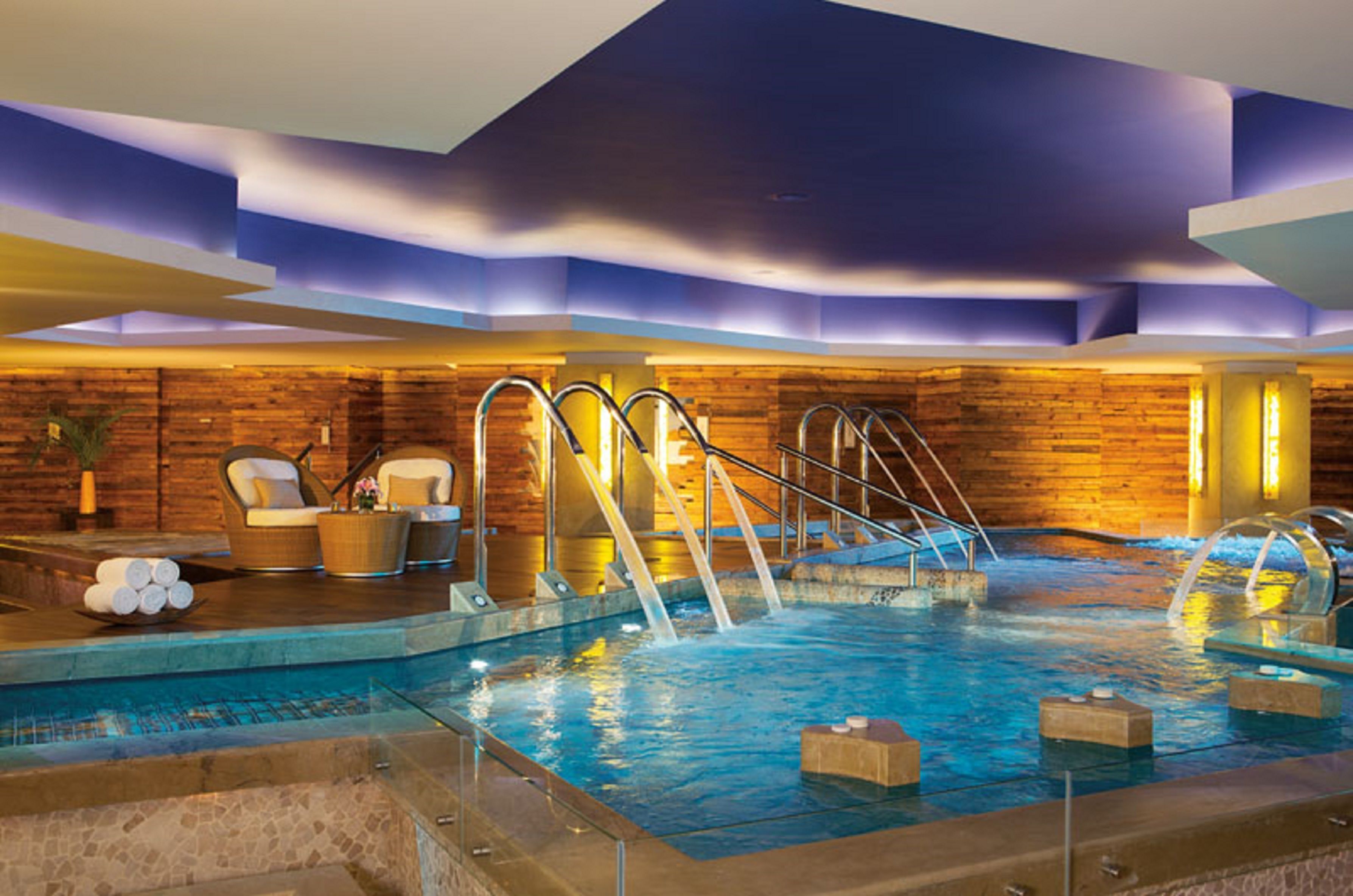 Un espace détente avec un jacuzzi, des sièges et un mur en bois.