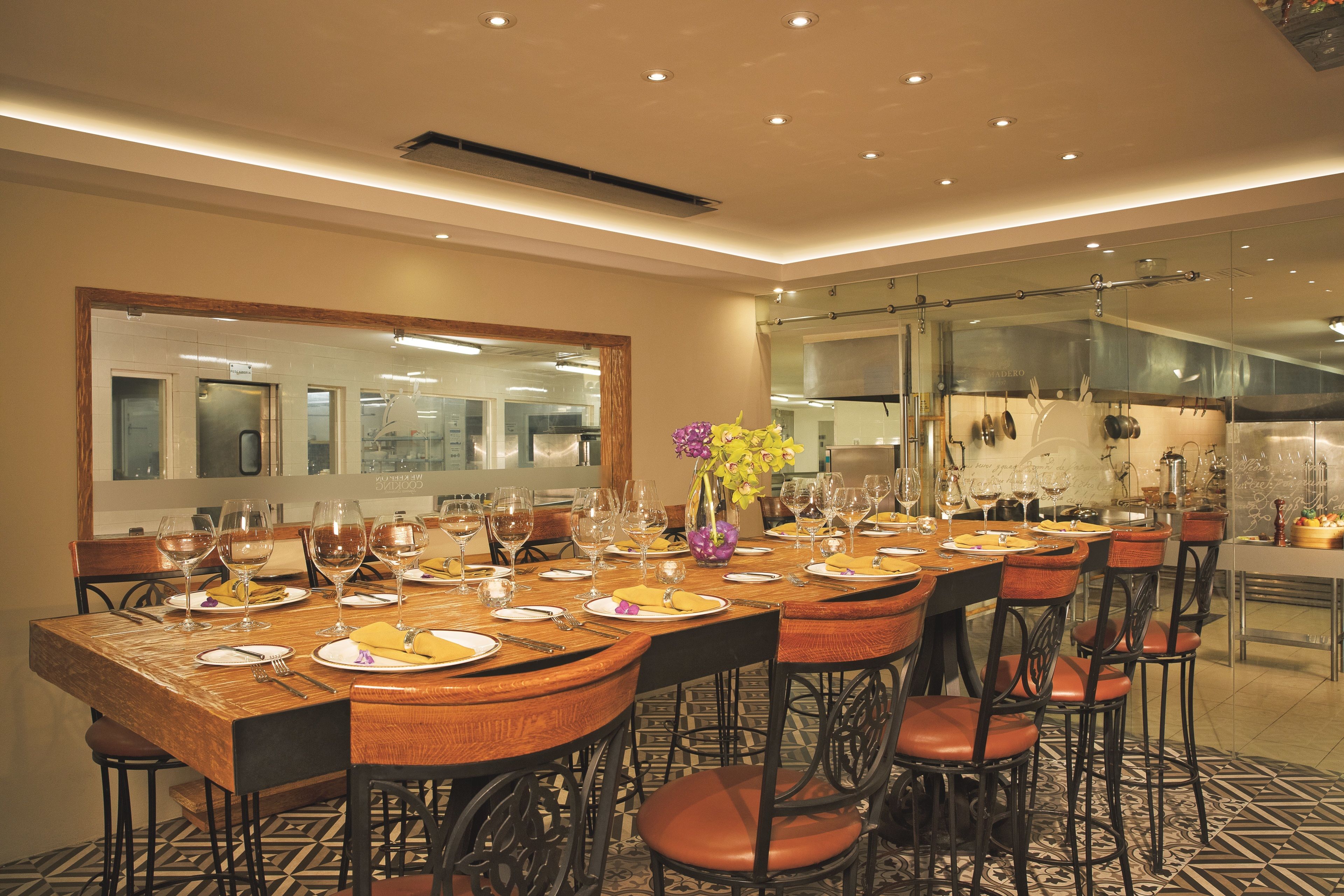 A dining area with a long wooden table set for multiple guests, surrounded by chairs.