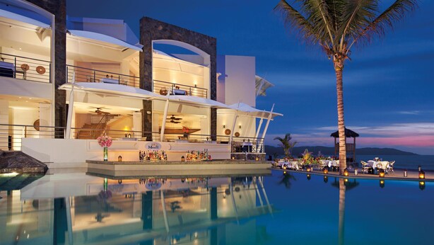 Un complexe hôtelier moderne doté d’une piscine, d’un espace extérieur aménagé et d’un bar.