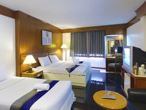 Une chambre d’hôtel avec deux lits, une télévision, un bureau et une chaise.