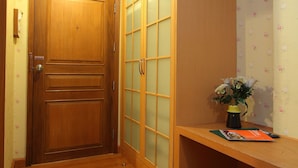 Una puerta de madera con un panel de vidrio satinado, un banco de madera y un jarrón con flores.