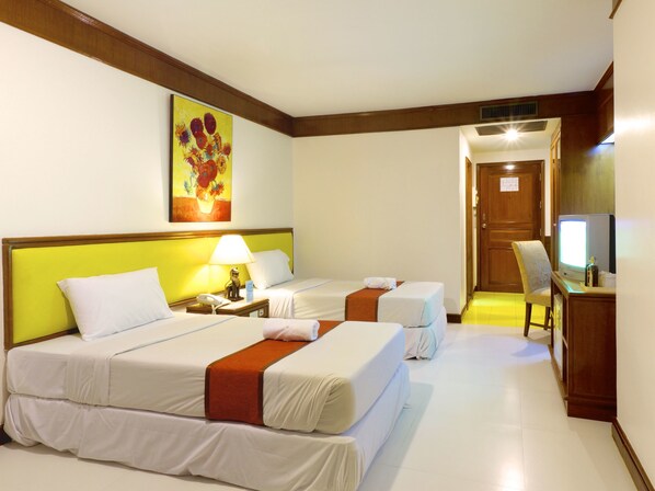 A hotel room with two beds, a desk with a computer, a chair, and a painting on the wall.