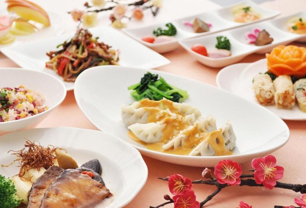 A variety of dishes on a table, including dumplings, a salad, and other Asian cuisine.