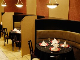 Un restaurante con asientos tipo cabina y mesas redondas, cada una con platos, vasos y cubiertos.