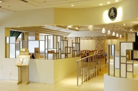 A modern hotel lobby with a reception desk, seating area, and a staircase.