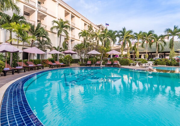 Una piscina al aire libre, sombrillas, sillones reclinables de piscina