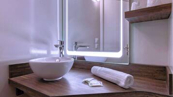 Une salle de bain avec un lavabo blanc, un miroir et un plan de toilette en bois.