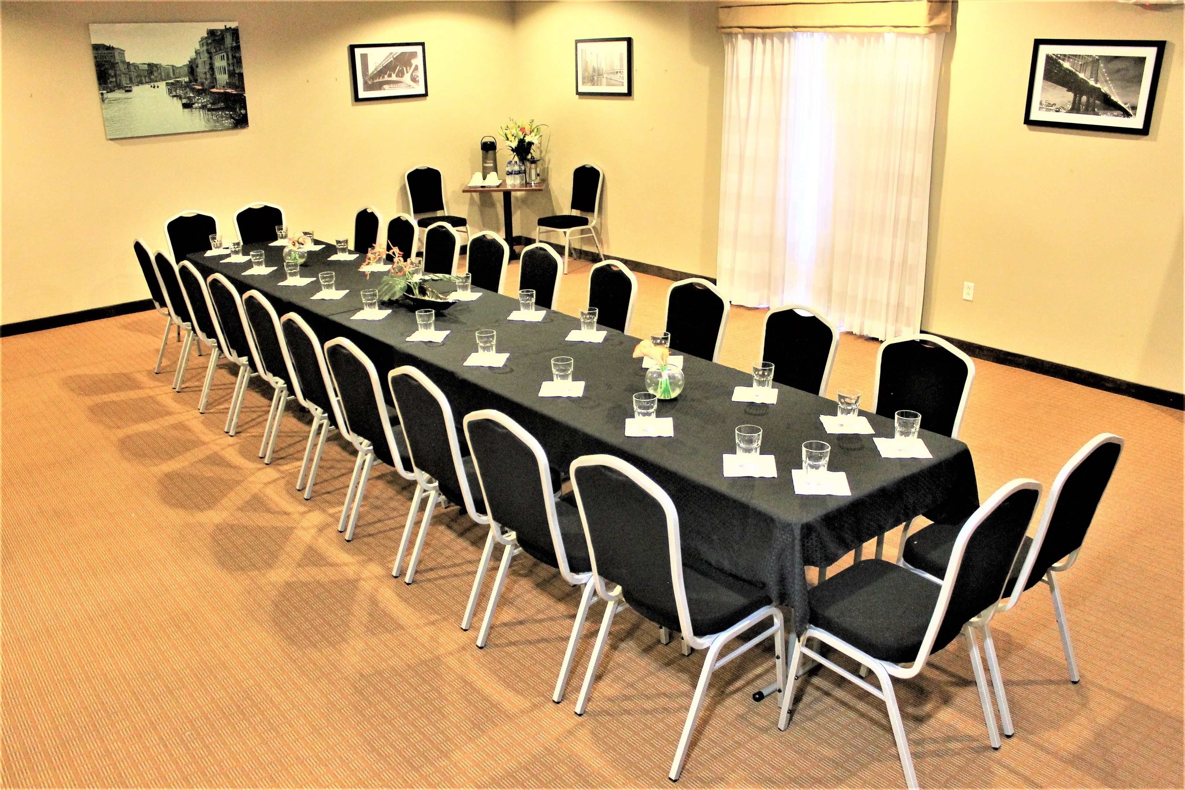A conference room with a long table, black chairs, and framed pictures on the walls.
