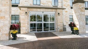 A building with a stone facade, a glass entrance, and potted plants.