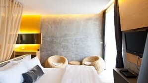 Habitació d'hotel amb un llit gran, dues butaques, un televisor i un escriptori.