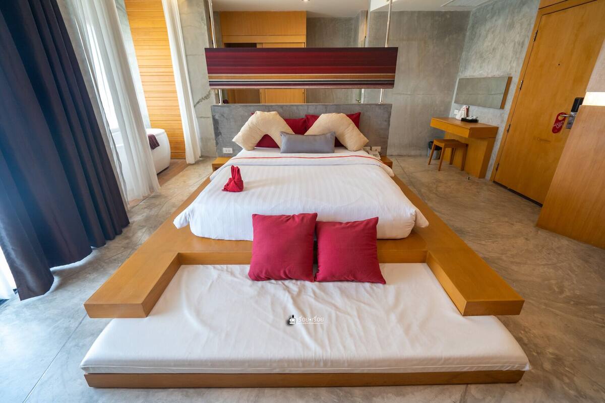 A modern hotel room with a large bed, a desk, and a wardrobe.