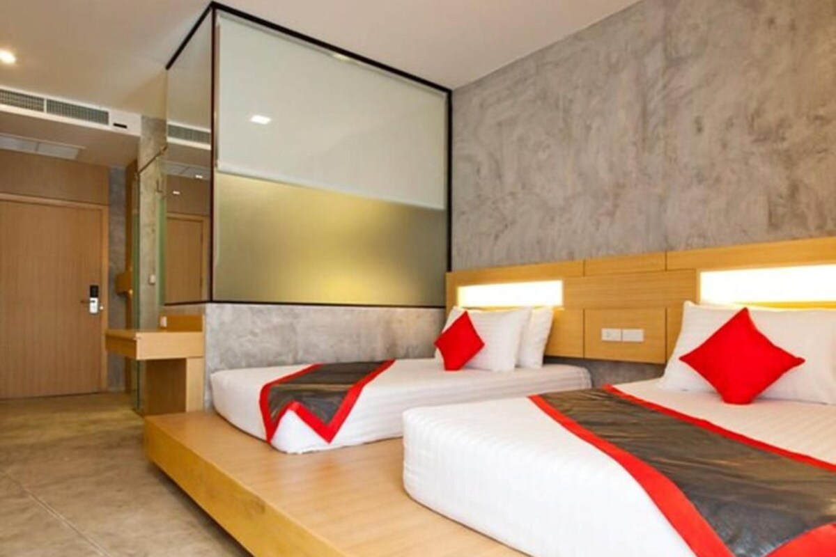 A hotel room with two beds, a large mirror, and a wooden headboard.