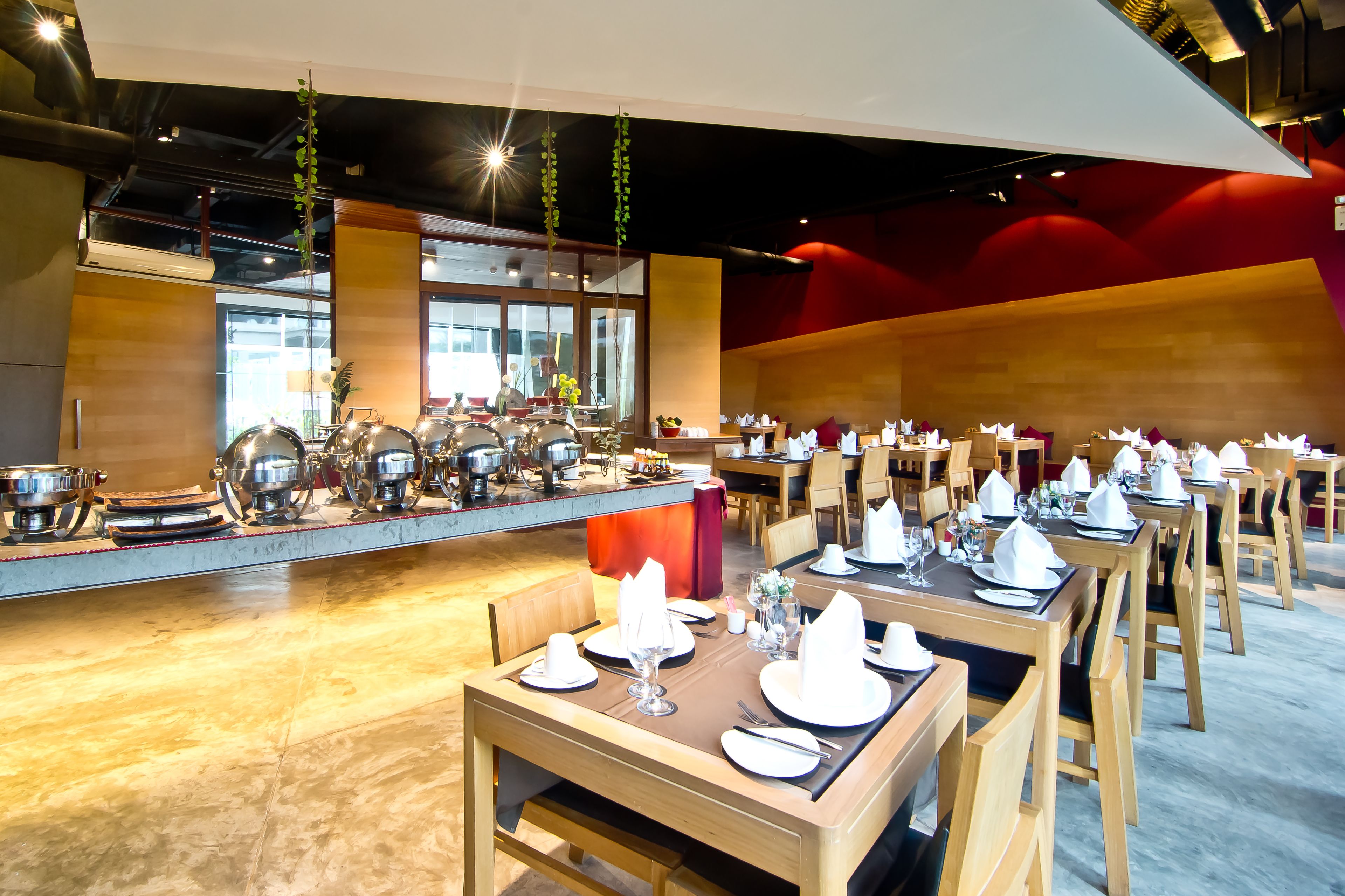 Ein Restaurant mit mehreren gedeckten Tischen, einer Theke mit Küchenutensilien und hängenden Pflanzen.