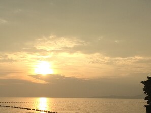 Tramonto sul mare calmo con un molo di protezione.