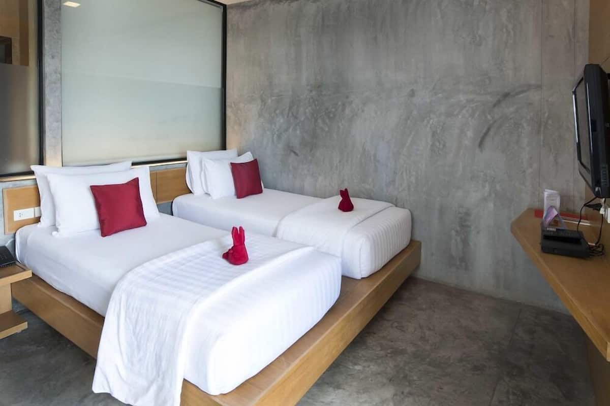 A hotel room with two beds, a television, and a large window.